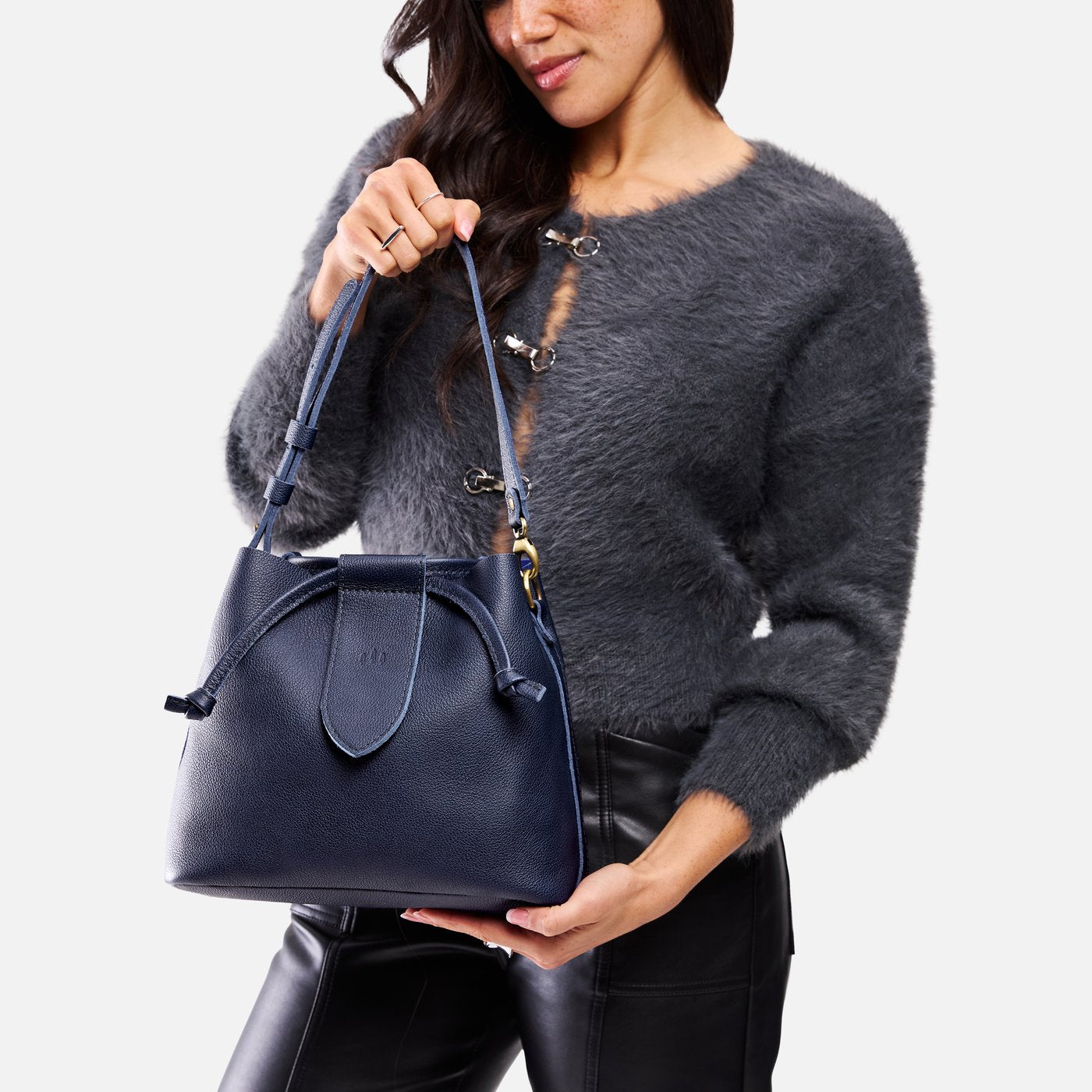 Cobalt*Large | Model holding symmetrical leather bag with leather drawstring closure and adjustable shoulder strap