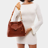 Nutmeg Large | Model holding symmetrical leather bag with leather drawstring closure and adjustable shoulder strap