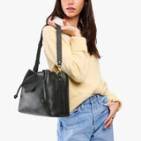 Pebbled--black Large | Model holding symmetrical leather bag with leather drawstring closure and adjustable shoulder strap