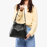 Pebbled--black Large | Model holding symmetrical leather bag with leather drawstring closure and adjustable shoulder strap