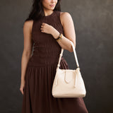 Pebbled Bone Large | Model holding symmetrical leather bag with leather drawstring closure and adjustable shoulder strap
