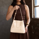 Pebbled Bone Large | Model holding symmetrical leather bag with leather drawstring closure and adjustable shoulder strap