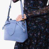 Aster Small | Model holding symmetrical leather bag with leather drawstring closure and adjustable shoulder strap
