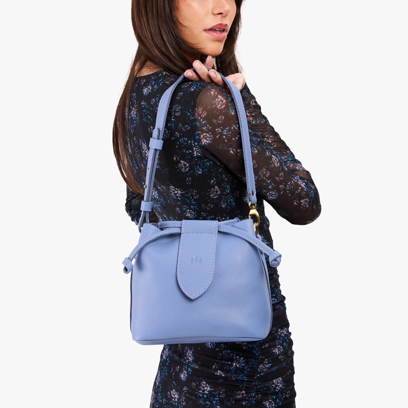 Aster*Small | Model holding symmetrical leather bag with leather drawstring closure and adjustable shoulder strap