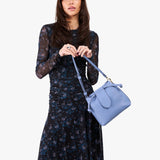 Aster Small | Model holding symmetrical leather bag with leather drawstring closure and adjustable shoulder strap