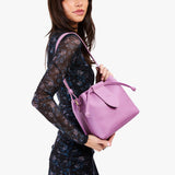 Calla Lily Small | Model holding symmetrical leather bag with leather drawstring closure and adjustable shoulder strap