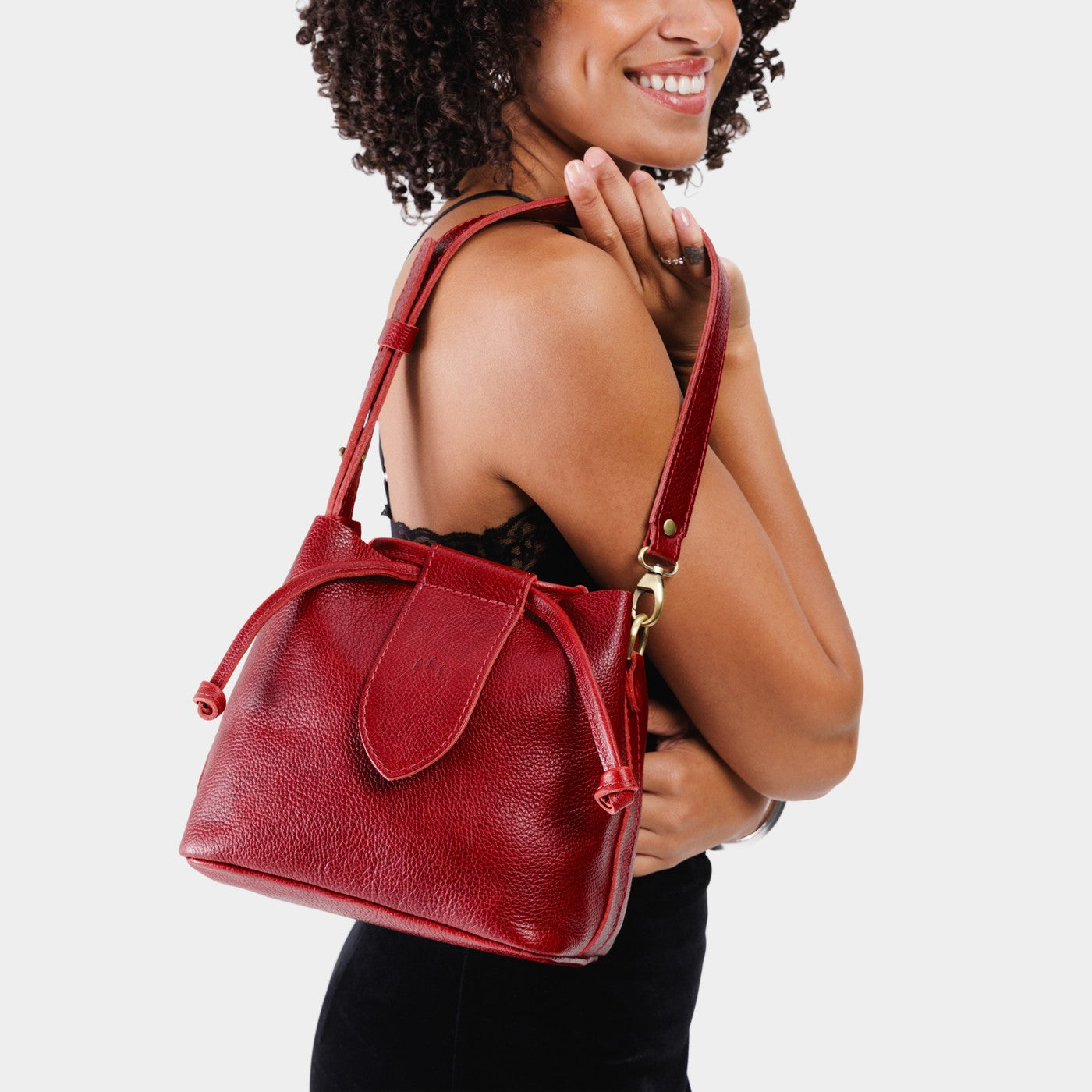 Chili Red*Small | Model holding symmetrical leather bag with leather drawstring closure and adjustable shoulder strap