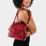 Chili Red Small | Model holding symmetrical leather bag with leather drawstring closure and adjustable shoulder strap