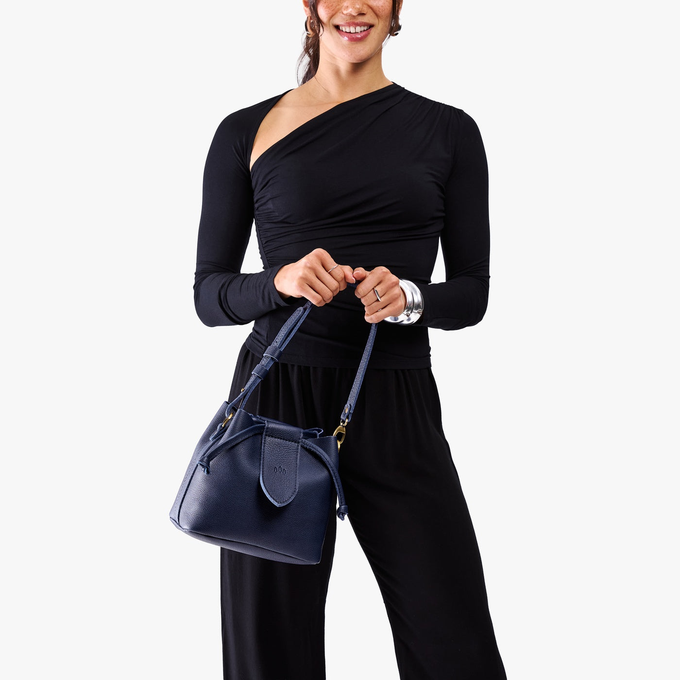 Cobalt*Small | Model holding symmetrical leather bag with leather drawstring closure and adjustable shoulder strap