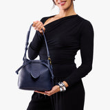 Cobalt Small | Model holding symmetrical leather bag with leather drawstring closure and adjustable shoulder strap