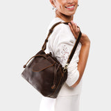 Coldbrew Small | Model holding symmetrical leather bag with leather drawstring closure and adjustable shoulder strap