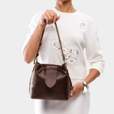 Coldbrew Small | Model holding symmetrical leather bag with leather drawstring closure and adjustable shoulder strap