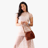 Nutmeg Small | Model holding symmetrical leather bag with leather drawstring closure and adjustable shoulder strap