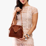 Nutmeg Small | Model holding symmetrical leather bag with leather drawstring closure and adjustable shoulder strap