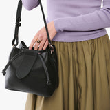 Pebbled--black Small | Model holding symmetrical leather bag with leather drawstring closure and adjustable shoulder strap