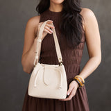 Pebbled Bone Small | Model holding symmetrical leather bag with leather drawstring closure and adjustable shoulder strap
