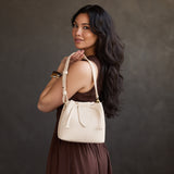Pebbled Bone Small | Model holding symmetrical leather bag with leather drawstring closure and adjustable shoulder strap