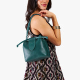 Sea Glass Small | Model holding symmetrical leather bag with leather drawstring closure and adjustable shoulder strap