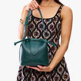 Sea Glass Small | Model holding symmetrical leather bag with leather drawstring closure and adjustable shoulder strap
