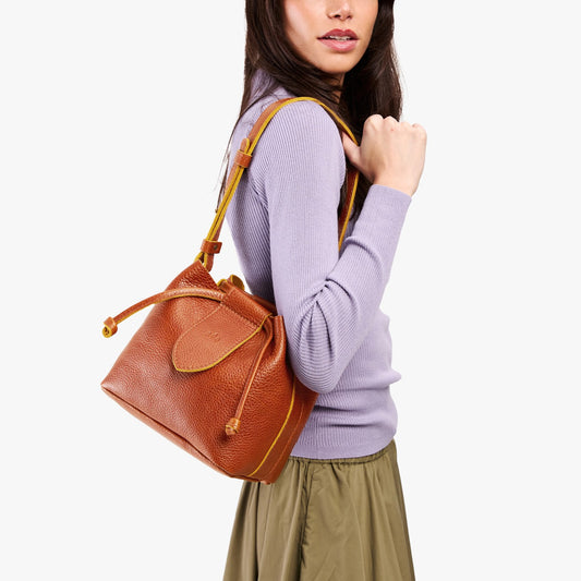 Sienna*Small | Model wearing symmetrical leather bag with leather drawstring closure and adjustable shoulder strap
