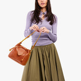 Sienna Small | Model holding symmetrical leather bag with leather drawstring closure and adjustable shoulder strap