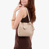 Oatmilk Small | Model holding symmetrical leather bag with leather drawstring closure and adjustable shoulder strap