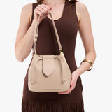 Oatmilk Small | Model holding symmetrical leather bag with leather drawstring closure and adjustable shoulder strap