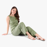 Crema | Person wearing light green cropped pants and cream flat sandals with an ankle strap and buckle, shown against a plain background.