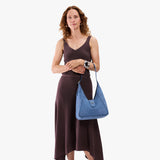 Cornflower | Model carrying structured hobo shoulder bag with floral patterned embossed leather, adjustable strap and magnetic closure
