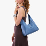 Cornflower | Model carrying structured hobo shoulder bag with floral patterned embossed leather, adjustable strap and magnetic closure