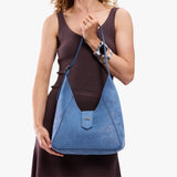 Cornflower | Model carrying structured hobo shoulder bag with floral patterned embossed leather, adjustable strap and magnetic closure