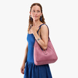 Hollyhock | Model carrying structured hobo shoulder bag with floral patterned embossed leather, adjustable strap and magnetic closure