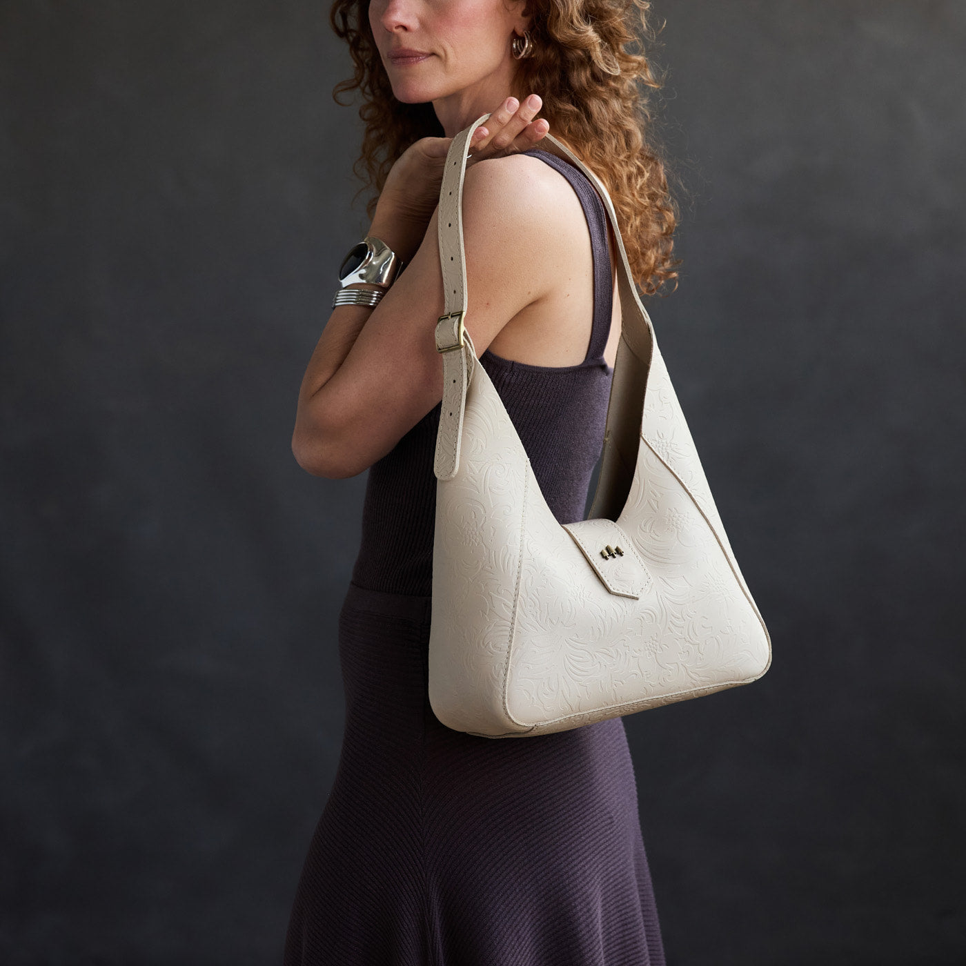 Jasmine | Model carrying structured hobo shoulder bag with floral patterned embossed leather, adjustable strap and magnetic closure