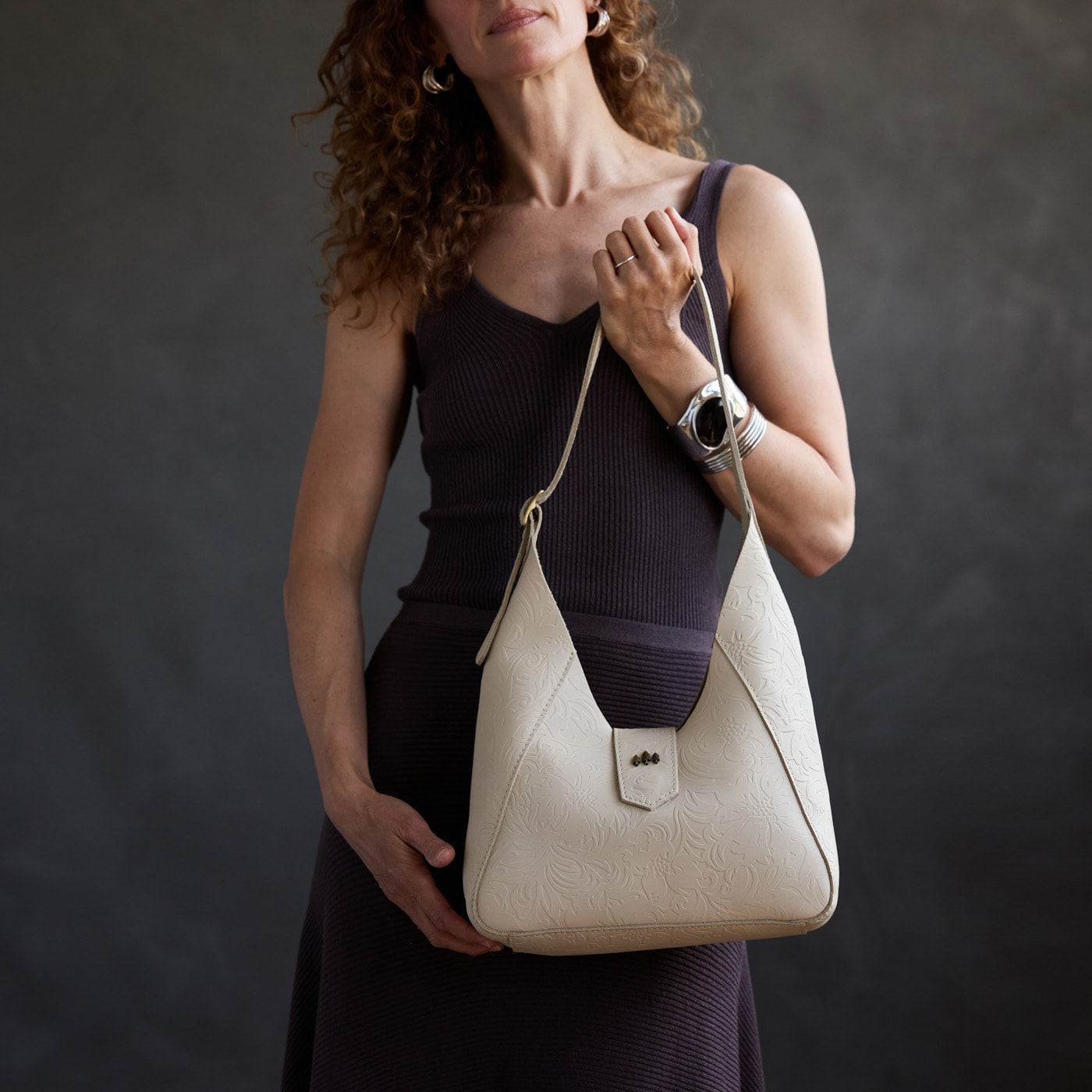 Jasmine | Model carrying structured hobo shoulder bag with floral patterned embossed leather, adjustable strap and magnetic closure