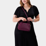 Lollipop Large | A large bowler styled bag with a crossbody strap being worn by a model wearing a black dress