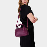 Lollipop Large | A large bowler styled bag with a crossbody strap being worn by a model wearing a black dress