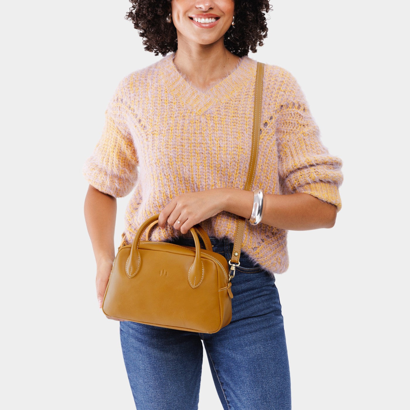 Mango*Large | A large bowler styled bag with a crossbody strap being worn by a model wearing a knit sweater and jeans