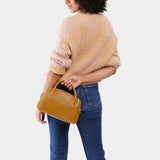 Mango Large | A large bowler styled bag with a crossbody strap being worn by a model wearing a knit sweater and jeans