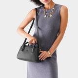 Pebbled--black Large | A bowler styled bag with a crossbody strap being held by a model wearing a dress