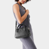 Pebbled--black Large | A bowler styled bag with a crossbody strap being held by a model wearing a dress
