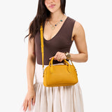 Sunshine Large | A large bowler styled bag with a crossbody strap being worn by a model in a neutral outfit