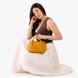 Sunshine Large | A large bowler styled bag with a crossbody strap being held by a model in a neutral outfit
