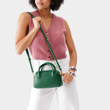Bacalar Small | A bowler styled bag with a crossbody strap being worn by a model wearing a pink knit vest
