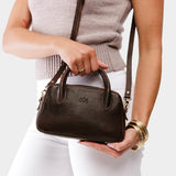 Coldbrew Small | A bowler styled bag with a crossbody strap being worn by a model wearing a knit top