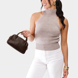 Coldbrew Small | A bowler styled bag with a crossbody strap being held by a model wearing a knit top