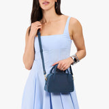 Deep Water Small | A bowler styled bag with a crossbody strap being worn by a model in a light blue dress