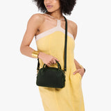 Evergreen Small | A bowler styled bag with a crossbody strap being worn by a model in a yellow dress