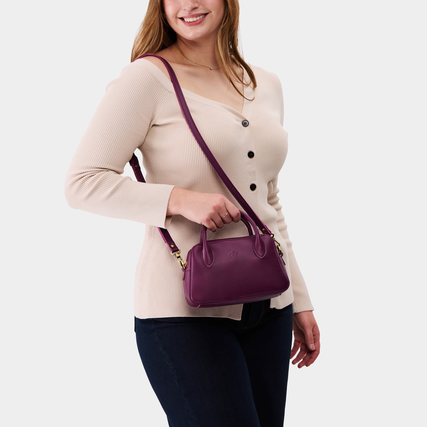 Lollipop*Small | A bowler styled bag with a crossbody strap being worn by a model wearing a taupe top
