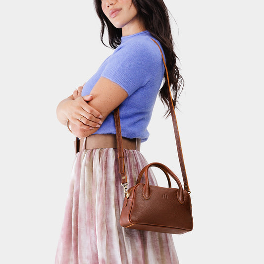 Nutmeg*Small | A Bowler style purse with a crossbody strap being worn by a model