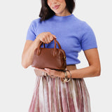 Nutmeg Small | A Bowler style purse with a crossbody strap being held by a model